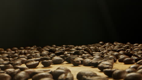 Ein-Haufen-Kaffeebohnen,-Die-Auf-Eine-Holzoberfläche-Geworfen-Werden