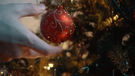 Hand,-Die-Goldene-Und-Rote-Kugel-Auf-Den-Weihnachtsbaum-Legt