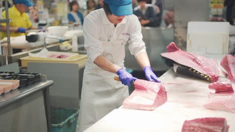 Skilled-Man-Slicing-Fresh-Bluefin-Tuna-In-Different-Portion-With-People-Watching-In-A-Fish-Market-At-Toretore-Ichiba,-Wakayama-Japan