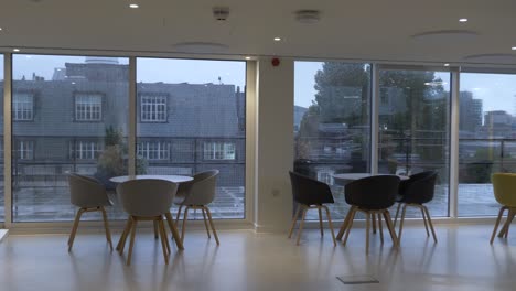 Moderne-Stühle-Und-Tische-Neben-Großen-Fenstern-Auf-Der-Büroterrasse