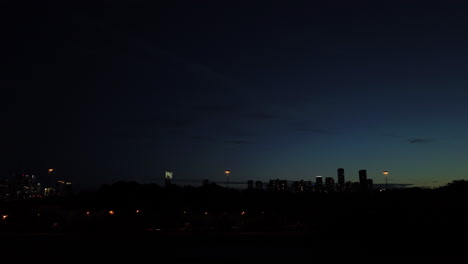 Wide-time-lapse-shot-of-rapid-city-skyline-sunset-with-fast-moving-vehicles-and-objects