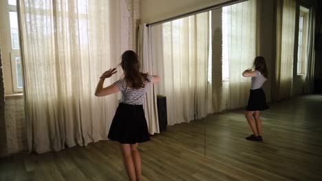 Teenage-girl-dancing-in-the-studio,-next-to-a-mirror-reflection-in-slow-motion
