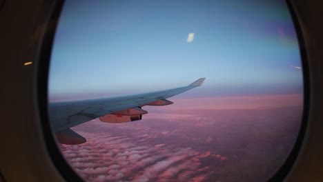 Blick-Aus-Dem-Flugzeugfenster-über-Hellrosa-Gefärbte-Wolken
