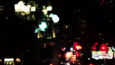 Driving-through-a-city-at-night-with-raindrops-on-the-window