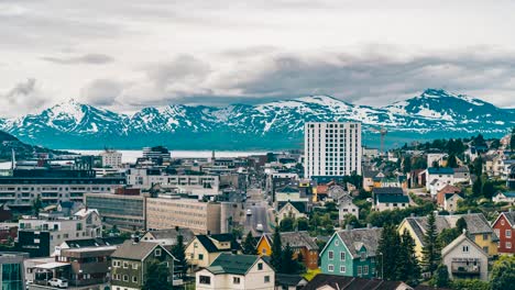 Timelapse-overlooking-Tromso-city-skyline,-during-summer,-mountains-on-the-horizon-and-clouds-moving-in