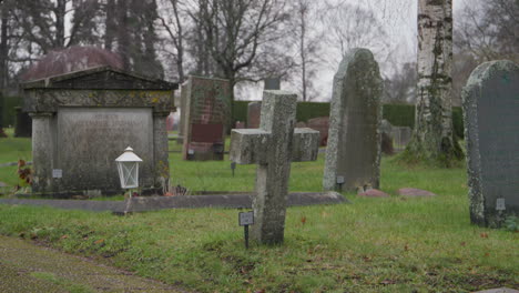 Stone-cross-and-gravestones-at-Stockholm-cemetery,-handheld-shot