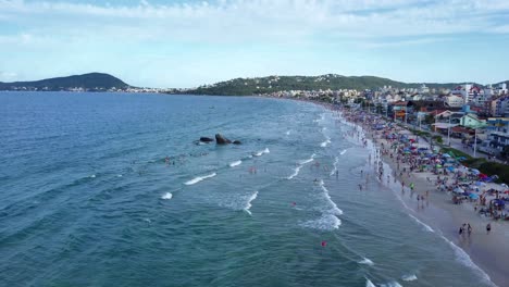 Aerial-static-shot-of-tourists-bathing-on-the-sea-in-Bombas-beach,-Brazil
