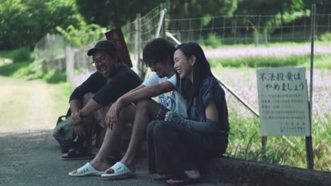 Few-Japanese-Friends-Laughing-While-Resting-Under-The-Shade-Outdoors-In-Kyoto,-Japan---full-slowmo-shot