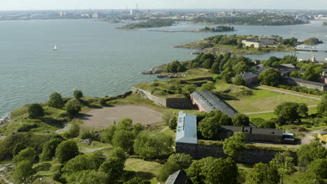 Aerial-view-tilting-over-the-Suomenlinna-fortress-island,-revealing-the-cityscape-of-Helsinki,-sunny,-summer-day,-in-Helsingfors,-Finland---tilt-up,-drone-shot