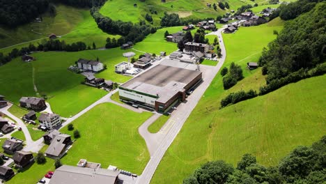 Aerial-orbiting-shot-of-mineral-water-plant-in-Elm,-Glarus,-Switzerland-60fps
