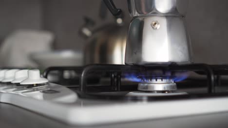 Gas-stove-with-blue-flames-and-coffee-in-moka-pot,-turning-on-by-hand,-extreme-closeup