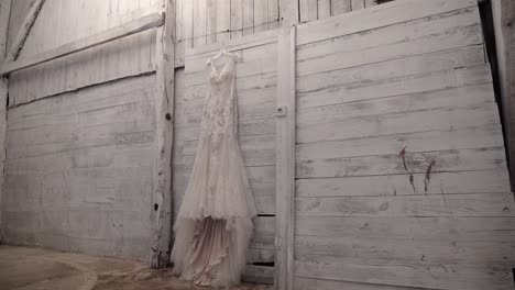Elegant-designer-wedding-gown-hanging-beautifully-on-a-white-wood-wall