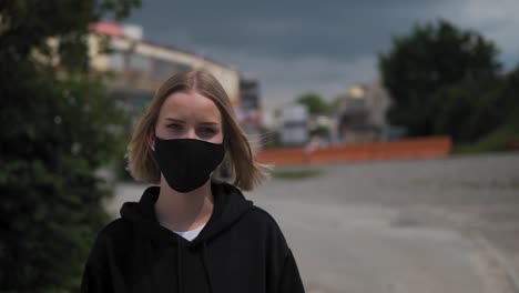 Portrait-of-Young-Woman-With-Black-Face-Mask-Looking-at-Camera-in-Urban-Exterior-Slow-Motion,-Covid-19-Virus-Pandemic-Outbreak-Concept