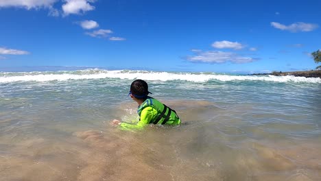 Boy-wearing-a-fluorescent-green-Life-Jacket-made-by-AIRHEAD-on-a-tropical-beach-vacation-on-the-BIG-ISLAND,-HAWAII-