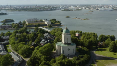 Aerial-view-away-from-the-church,-at-the-Suomenlinna-fortress,-Pikku-Musta-island-in-the-background,-sunny,-summer-day,-in-Helsinki,-Finland---reverse,-tilt-up,-drone-shot