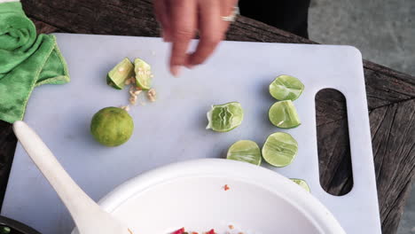 Woman-using-Kitchen-knife-to-slice-and-remove-fresh-lime-seeds---White-cutting-board