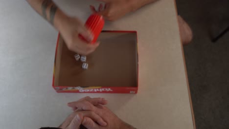 Bird's-eye-view-of-man-rolling-dice-on-a-small-fold-out-table