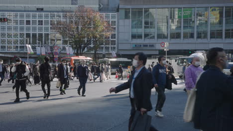 Fußgänger-Mit-Gesichtsmaske,-Die-Während-Einer-Pandemie-In-Tokio,-Japan,-Auf-Der-Belebten-Straße-Des-Shibuya-Kreuzes-Vorbeikommen