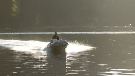 Male-in-Motorboat-Moving-at-Water-of-Alaskan-Bay-on-Summer-Evening-With-Sunlight-as-Backlight,-Slow-Motion