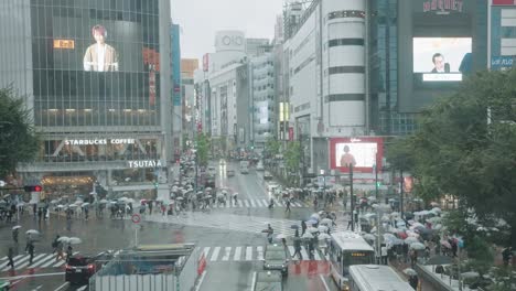 People-With-Umbrellas-Walking-At-Shibuya-Crossing-In-Tokyo-On-A-Rainy-Day---high-angle,-slow-motion