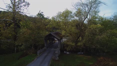 Aerial-Drone-Pull-Back-shot-of-a-wooden-covered-bridge-during-fall-in-the-country