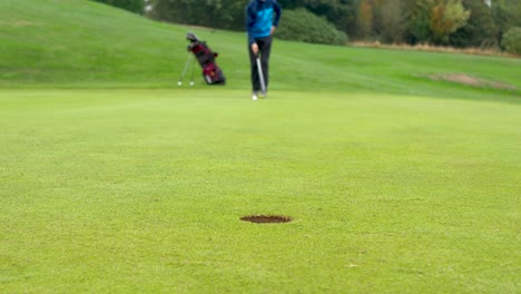 Blurred-out-golfer-lining-up-for-a-medium-length-putt-with-focus-on-the-hole