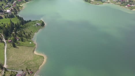 Aerial-High-Altitude-shot-of-lake---reservoir-front-where-water-meets-land-with-clear-water-and-roads