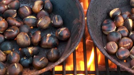 Chestnuts-roasted-on-open-fire,-seasonal-delicacy,-harvest,-1920-HD,-holiday-favorite-food,-close-up,-roasting-in-iron-pan,-dolly-sliding-shot-right-to-left