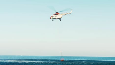 Hubschrauber-Fliegt-Nach-Dem-Füllen-Eines-Wassereimers-Los,-Um-Zum-Waldbrand-Zu-Fliegen