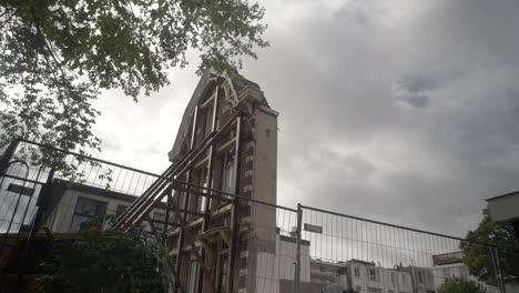 La-Fachada-De-Un-Edificio-Clásico-De-Amsterdam,-Con-árboles-Balanceándose-En-Primer-Plano-Y-Cielos-Nublados