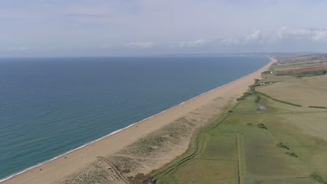 Luftaufnahme-Nach-Vorne-Hoch-über-Chesil-Beach-In-Abbotsbury-Mit-Blick-Entlang-Der-Küste-Im-Westen