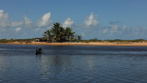 Static-shot-of-a-lone-fisherman-rowing-a-small-wooden-fishing-boat-on-the-Itaunas-River-in-Brazil