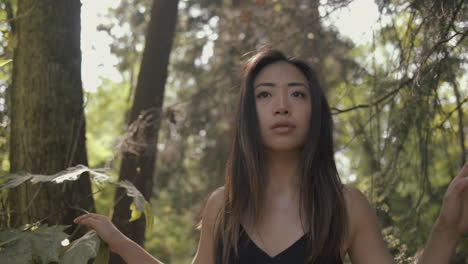 Closeup-of-asian-woman-in-black-looking-around-and-exploring-sunny-forest,-Lens-flares,-Slowmo