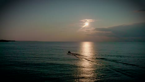 Luftaufnahmen-Eines-Bootes,-Das-Bei-Einem-Wunderschönen-Sonnenuntergang-über-Den-See-Rast