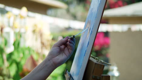 SLOW-MOTION-video-of-female-artists-hand-painting-on-canvas-with-blurred-background