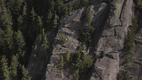 Aerial-Drone-Shot-Flying-Up-Past-Jagged-Rocky-Cliffs-On-Mountain