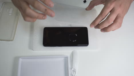 Man-carefully-applies-the-screen-protector-on-a-smartphone-after-applying-the-glue