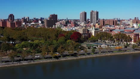 Long-drone-follow-of-yellow-school-bus-down-the-FDR-Drive-along-the-Harlem-River-in-Harlem,-Manhattan,-NYC