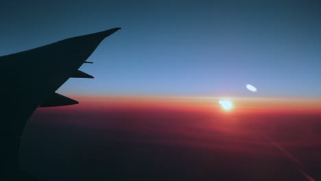 Early-morning-sunrise-over-the-wing-of-a-big-passenger-airplane-in-crystal-blue-skies