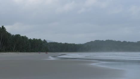 Slow-motion-shot-of-wide-and-long-sandy-beach-with-palm-trees-and-cloudy-sky-in-Asia