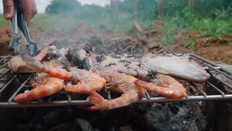 Flipping-shrimp-on-a-rustic-makeshift-wood-barbecue-grill-in-Spain,-SLOW-MOTION