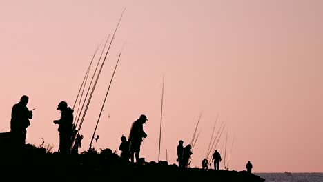 Group-of-fishermen-standing-on-the-bay,-preparing-their-fishing-rods