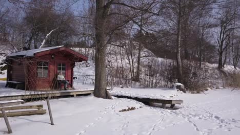 Depressed-young-caucasian-woman-sitting-all-by-herself-in-front-of-a-cute-red-cabin