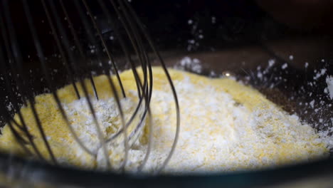 Mixing-dry-cornmeal-and-cornstarch-ingredients-with-whisk,-Slow-Motion-Close-Up