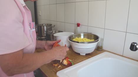 Senior-lady-cooking-at-home,-washing-and-cleaning-paprika-in-the-kitchen-sink