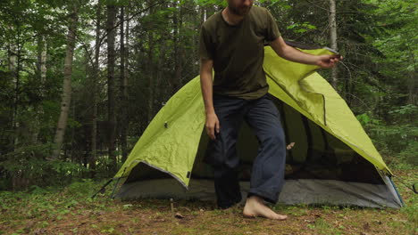Man-getting-out-of-a-small-camping-tent's-door