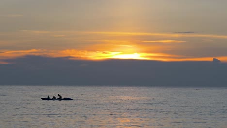 Touristen-In-Einem-Ruderboot-Bei-Farbenfrohem-Orangefarbenem-Sonnenuntergang,-Silhouetten-Vor-Der-Untergehenden-Sonne