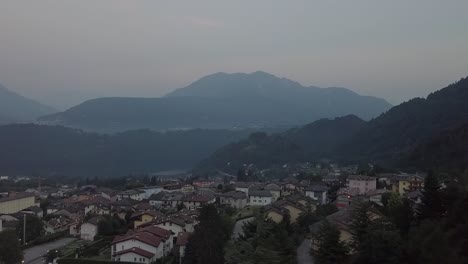 Aerial-panoramic-view-of-Levico-Terme,-Italy,-during-sunrise-with-drone-flying-sideways