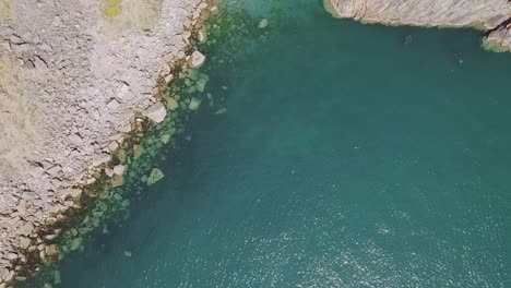 Aerial-Top-Down-shot-of-beautiful-water,-revealing-a-Bay-and-Cliffside
