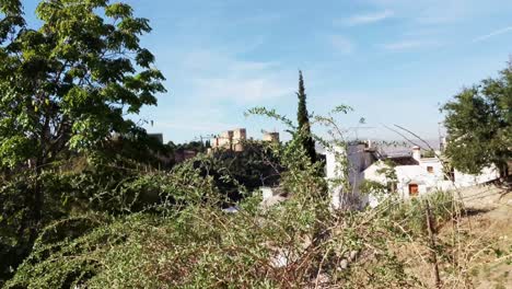 Die-Berühmte-Alhambra-Erscheint-In-Einiger-Entfernung-Hinter-Einer-Kopfsteinpflastermauer,-Während-Die-Kamera-Leicht-Nach-Oben-Fährt